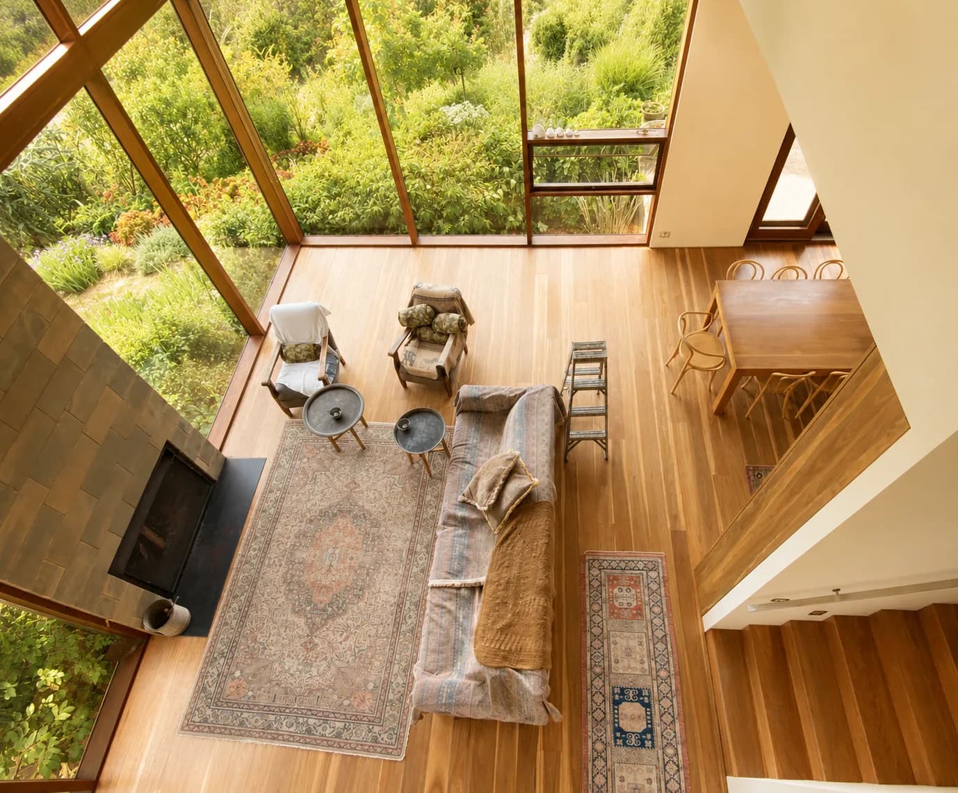 A timber-lined living space photographed from above, with full-height glazing onto a garden.