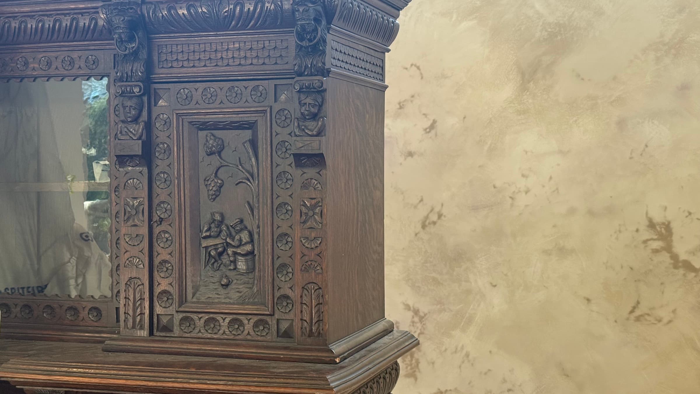 A hand-finished mineral wall with soft tonal variation, beside a carved dark-oak cabinet.